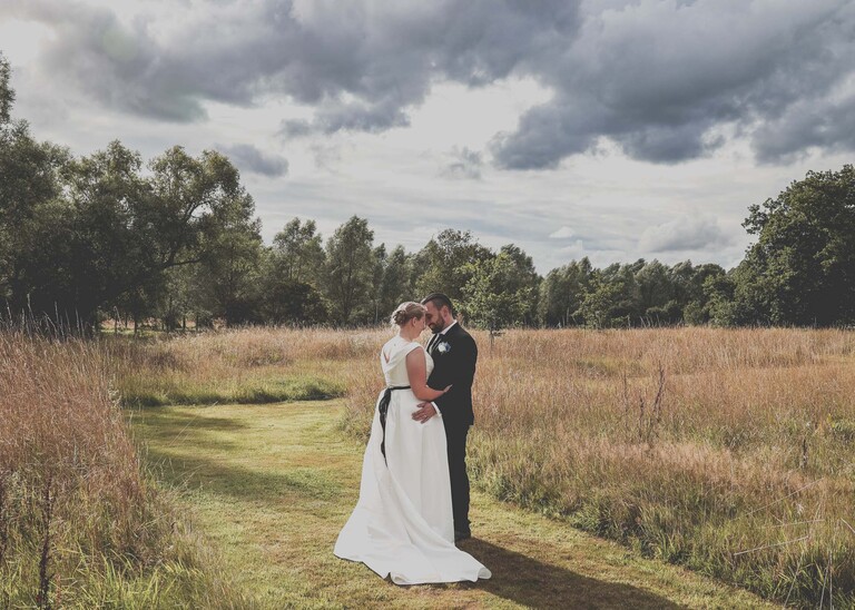 A bride and groom in a meadow with their heads touching on a wedding day at Easton Grange captured by Suffolk Wedding Photographer Hayley Denston Photography 