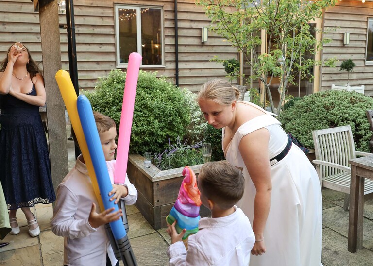 A bride talking to small children who all have foam tubes on a wedding day at Easton Grange captured by Suffolk Wedding Photographer Hayley Denston Photography 