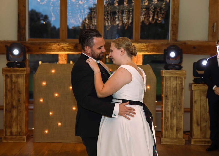 A bride and groom having their first dance with twinkly lights behind them on a wedding day at Easton Grange captured by Suffolk Wedding Photographer Hayley Denston Photography 