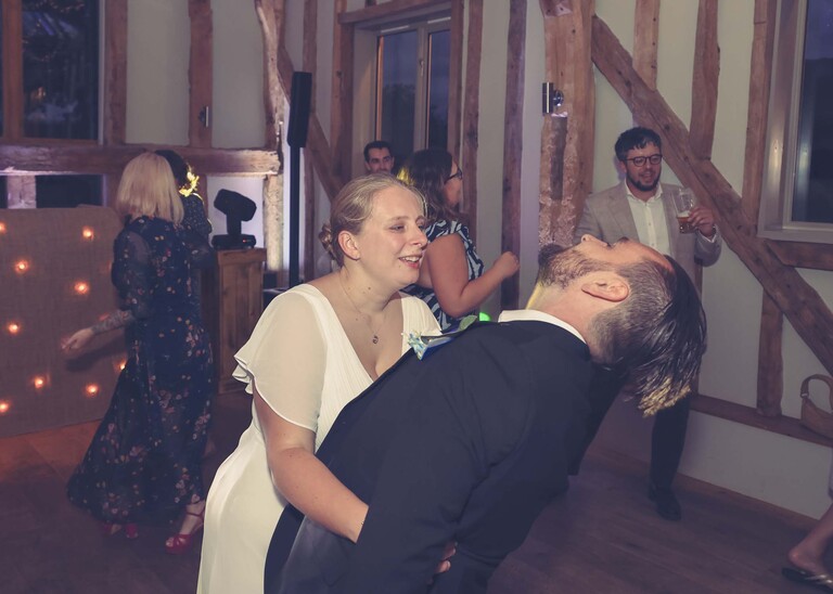 A groom being dipped by the bride during dancing on a wedding day at Easton Grange captured by Suffolk Wedding Photographer Hayley Denston Photography 