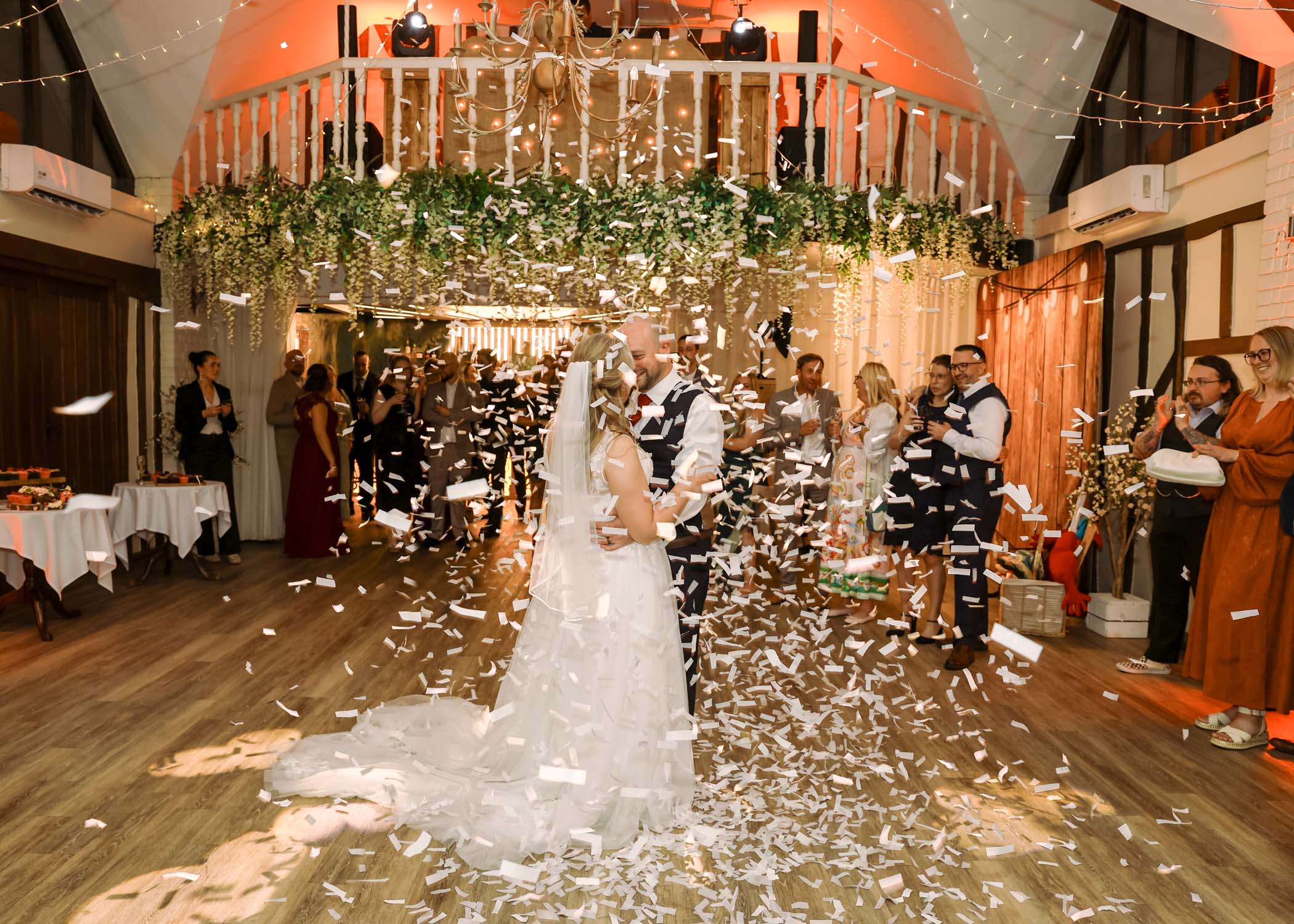 A bride and groom during their first dance with metallic confetti falling on them on a wedding day at Seckford Hall photographed by Suffolk Wedding Photographer Hayley Denston Photography