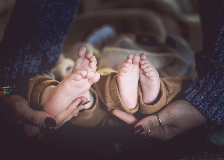 Two twin babies feet being held by their mums hands captured by Suffolk Portrait Photographer Hayley Denston Photography