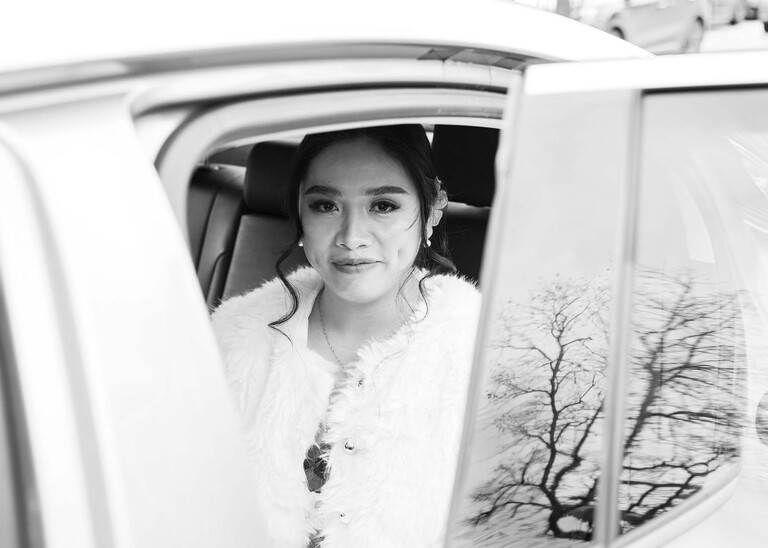 A black and white photo through a gap in the car as she arrives on her wedding day bury st edmunds on a wedding day photographed by suffolk wedding photographer Hayley Denston Photography