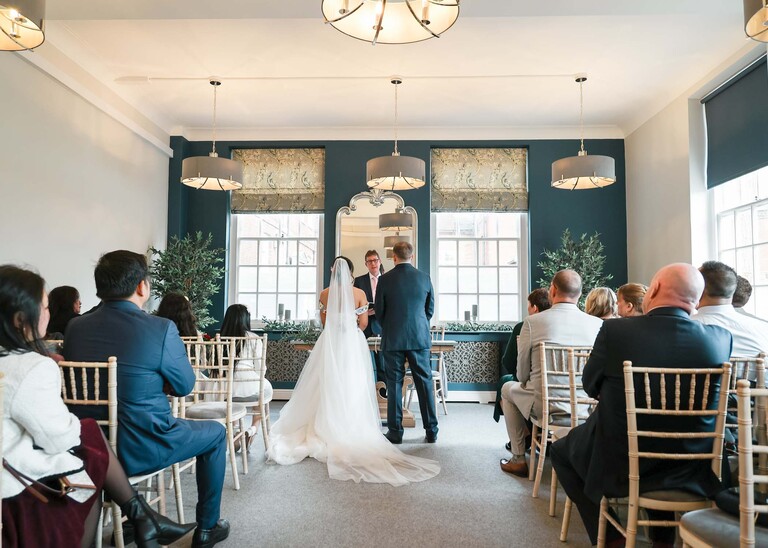 A bride and groom and all their guests from behind at Bury St Edmunds Registry Office photographed by Suffolk Wedding Photographer Hayley Denston Photography