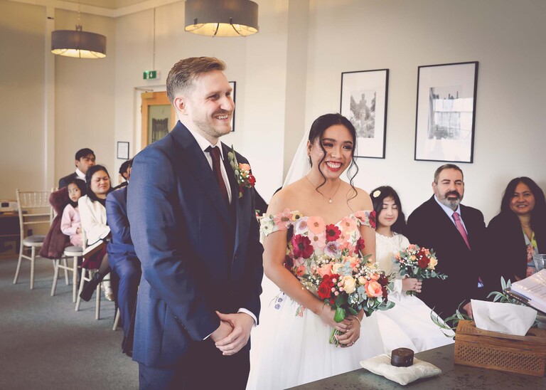 A bride and groom laughing during their wedding ceremony at Bury St Edmunds Registry Office photographed by Suffolk Wedding Photographer Hayley Denston Photography