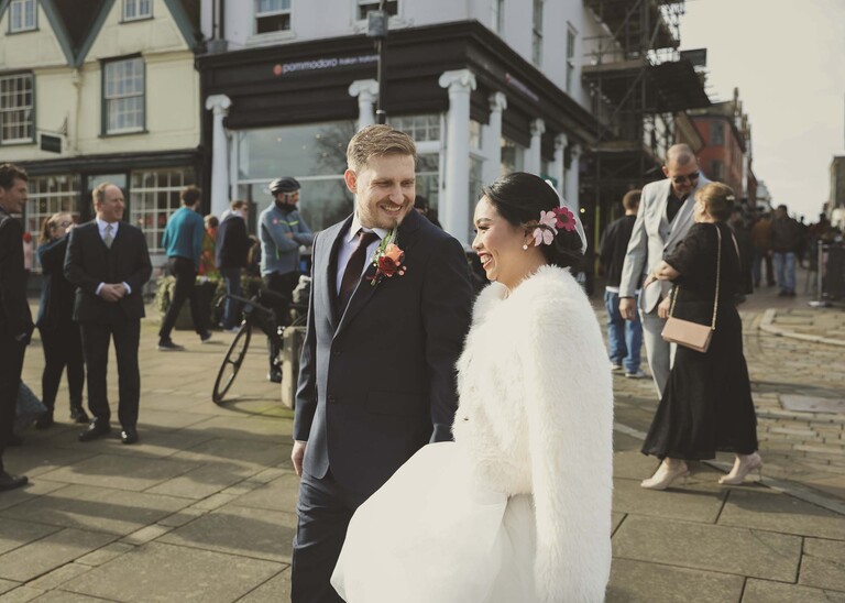 A bride and groom walking through bury st edmunds on a wedding day photographed by Suffolk Wedding Photographer Hayley Denston Photography