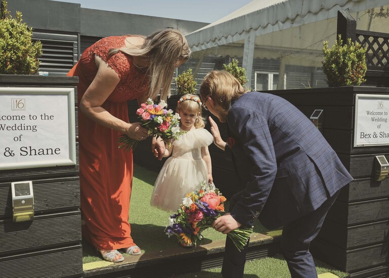 A little flower girl giving a high five to a groomsman on a wedding day at Venue 16 captured by suffolk wedding photographer Hayley Denston Photography