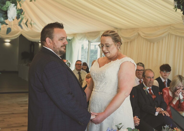 A bride and groom holding hands during their wedding ceremony on a wedding day at Venue 16 captured by suffolk wedding photographer Hayley Denston Photography