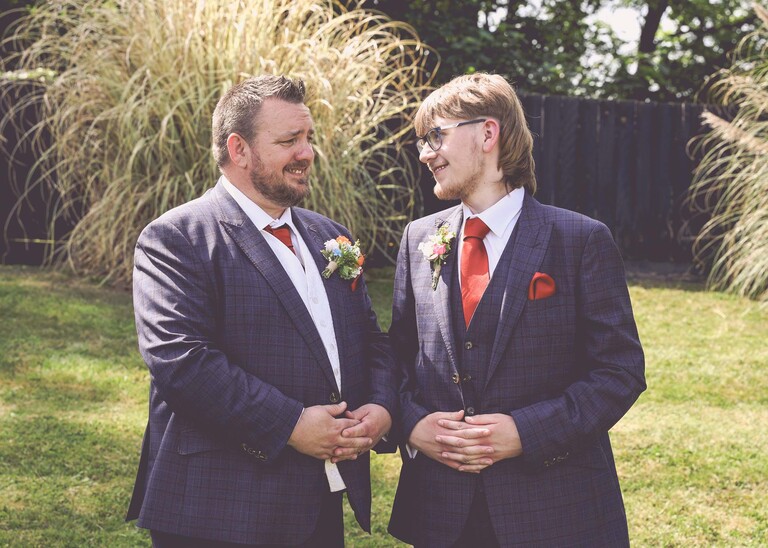 A groom and his stepson shaking hands and looking at each other on a wedding day at Venue 16 captured by suffolk wedding photographer Hayley Denston Photography