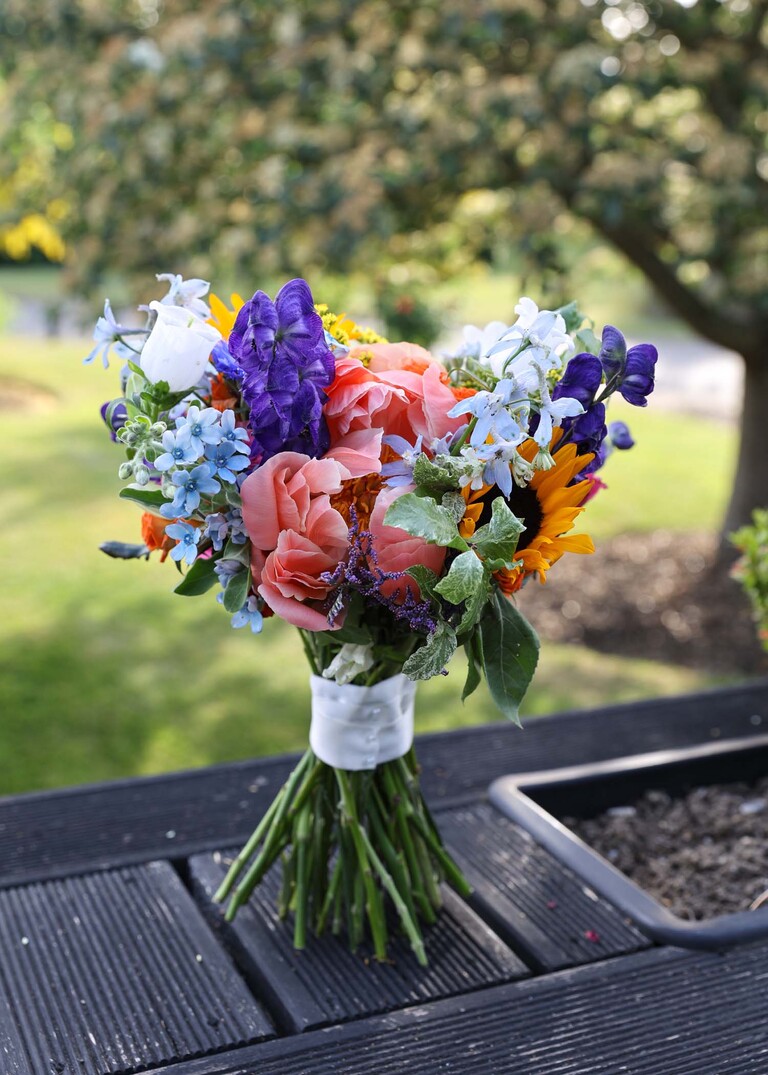 A bright multicoloured bridal bouquet stood up on it's stems on a wedding day at Venue 16 captured by suffolk wedding photographer Hayley Denston Photography