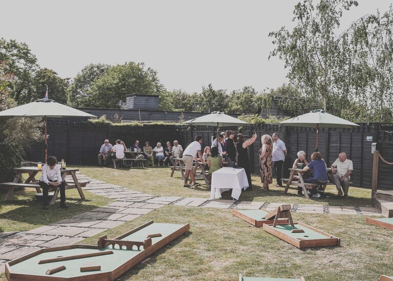 Guests mingling on a hot summers day at a wedding reception underneath garden parasols on a wedding day at Venue 16 captured by suffolk wedding photographer Hayley Denston Photography