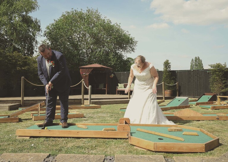 A bride and groom playing mini golf at their wedding receptionon a wedding day at Venue 16 captured by suffolk wedding photographer Hayley Denston Photography