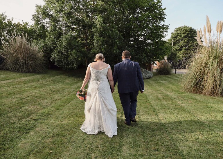 A bride and groom holding hands and walking away in the evening on a wedding day at Venue 16 captured by suffolk wedding photographer Hayley Denston Photography
