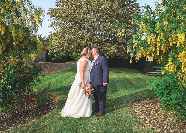 A bride and groom kissing amongst trees in the evening on a wedding day at Venue 16 captured by suffolk wedding photographer Hayley Denston Photography