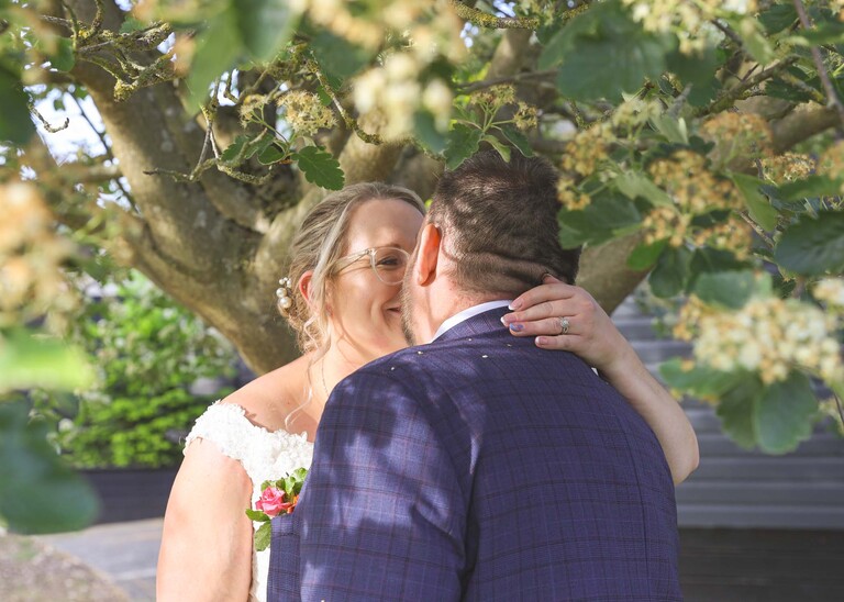 A bride and groom kissing underneath a tree on a wedding day at Venue 16 captured by suffolk wedding photographer Hayley Denston Photography