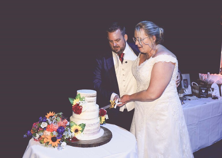 A bride and groom cutting their cake on a wedding day at Venue 16 captured by suffolk wedding photographer Hayley Denston Photography