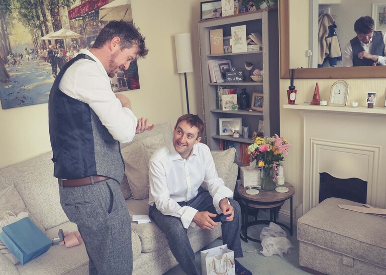 A bestman looking at cufflinks the groom has bought him with the groom watching on a wedding day at Haughley Park Barn photographed by suffolk wedding photographer Hayley Denston Photography