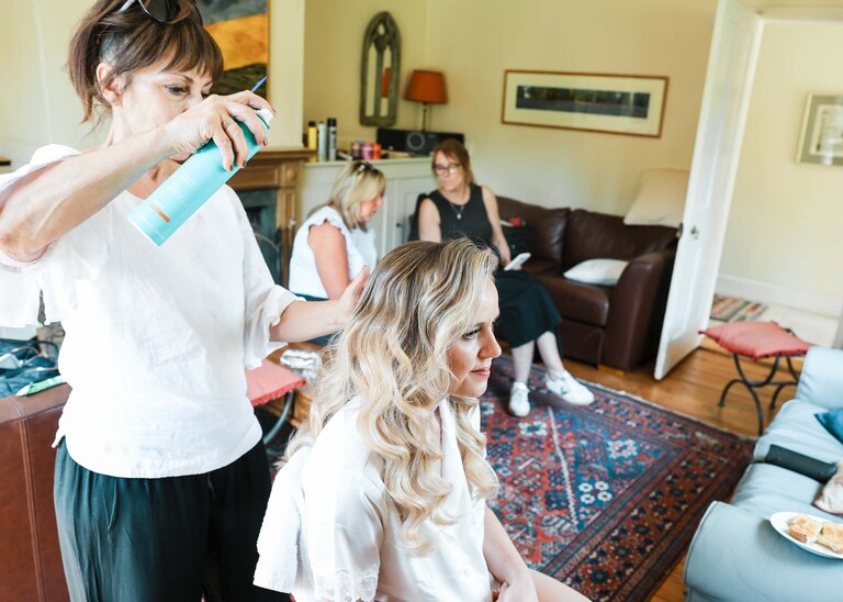 A bride having her hair done on a wedding day at Haughley Park Barn photographed by suffolk wedding photographer Hayley Denston Photography