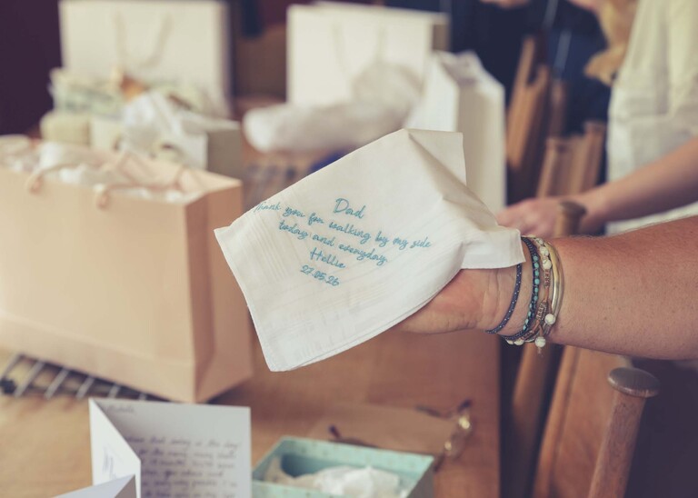 An embroidered handkerchief given to the brides dad by the bride with a message on it on a wedding day at Haughley Park Barn photographed by suffolk wedding photographer Hayley Denston Photography