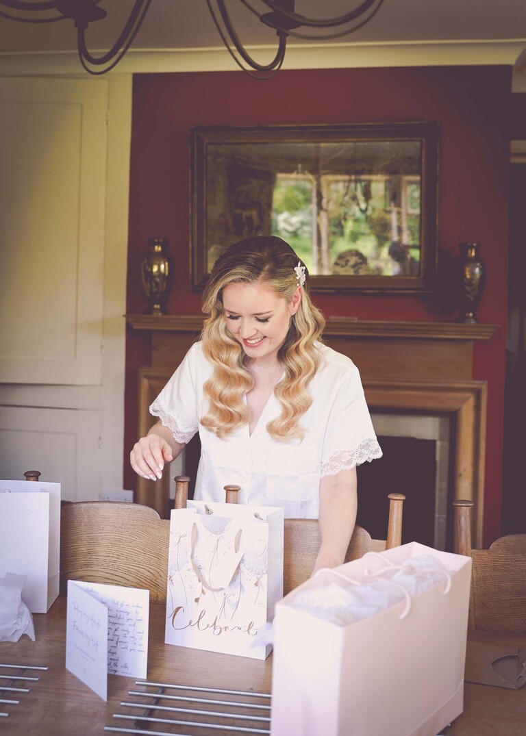 A bride opening a gift bag from her groom on a wedding day at Haughley Park Barn photographed by suffolk wedding photographer Hayley Denston Photography