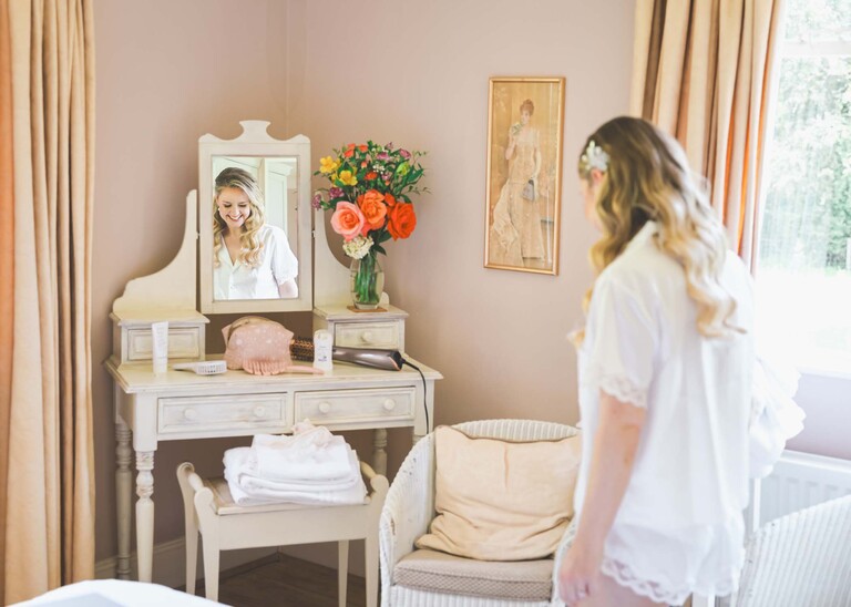A bride reflected in a dressing table mirror on a wedding day at Haughley Park Barn photographed by suffolk wedding photographer Hayley Denston Photography