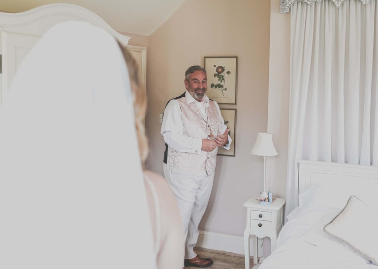 Looking over a brides shoulder as her dad sees her for the first time in her wedding dress on a wedding day at Haughley Park Barn photographed by suffolk wedding photographer Hayley Denston Photography