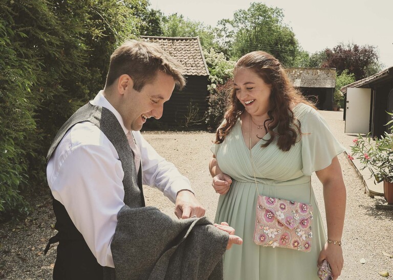 A groom showing his sister details on his jacket on a wedding day at Haughley Park Barn photographed by suffolk wedding photographer Hayley Denston Photography