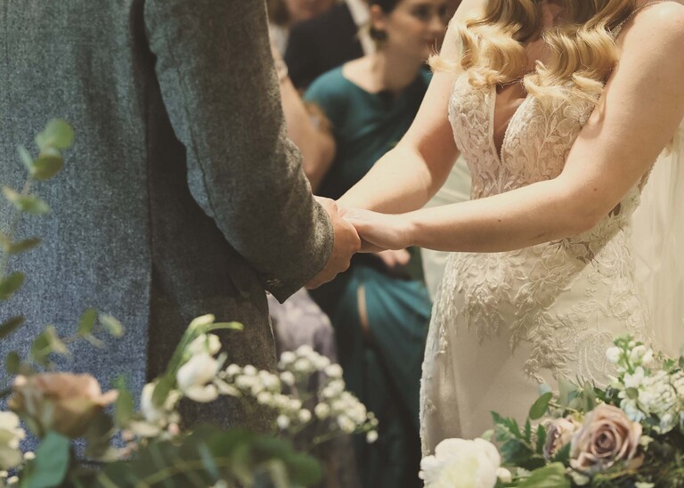 A bride and groom holding hands during their wedding ceremony on a wedding day at Haughley Park Barn photographed by suffolk wedding photographer Hayley Denston Photography