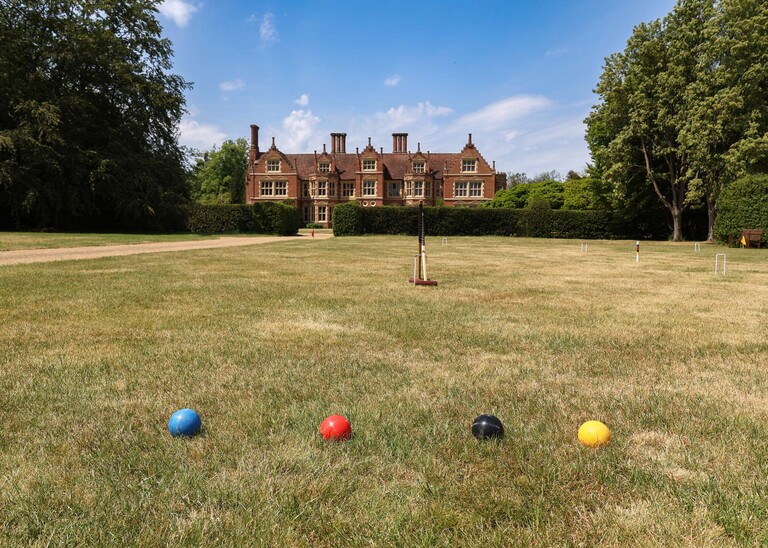 Croquet set up in front of a wedding venue on the lawn with bright blue skies on a wedding day at Haughley Park Barn photographed by suffolk wedding photographer Hayley Denston Photography