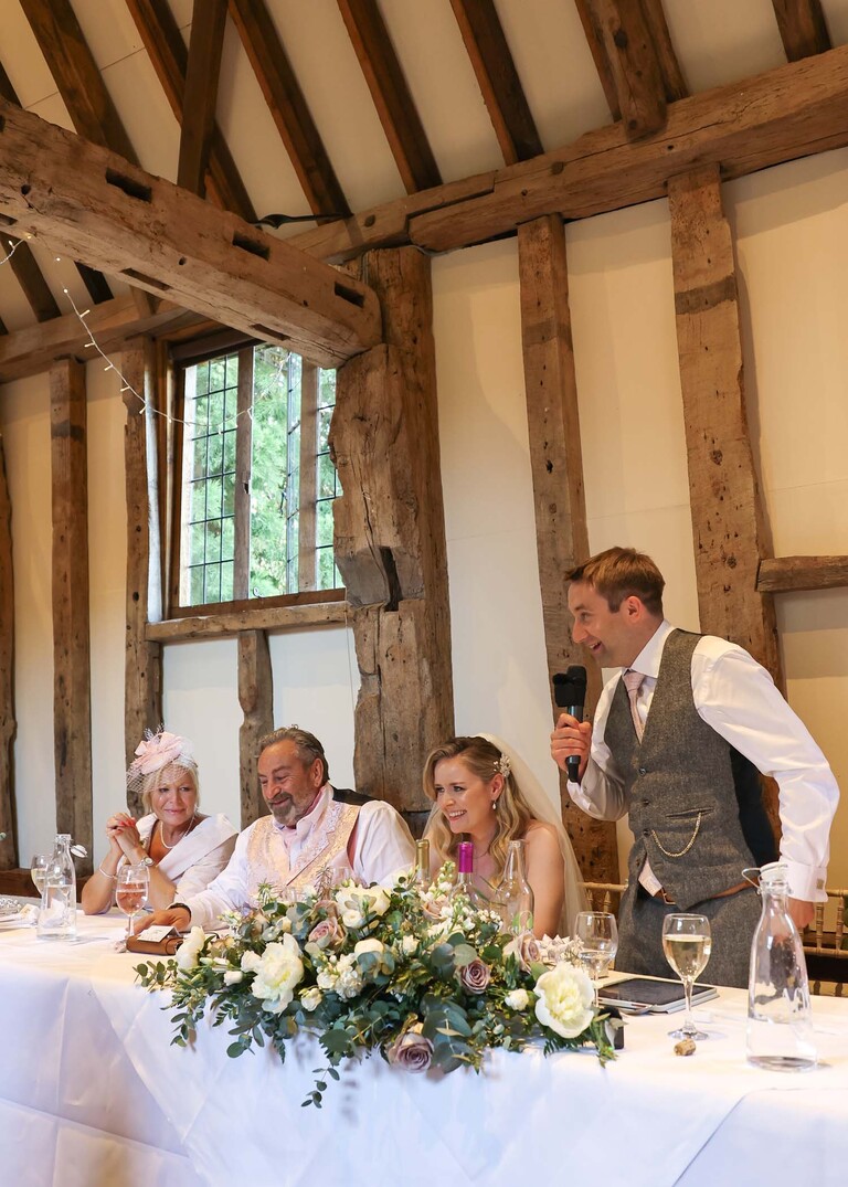 A groom giving his wedding speech from the top table on a wedding day at Haughley Park Barn photographed by suffolk wedding photographer Hayley Denston Photography