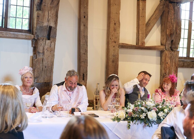 The top table laughing during the bestmans speech on a wedding day at Haughley Park Barn photographed by suffolk wedding photographer Hayley Denston Photography