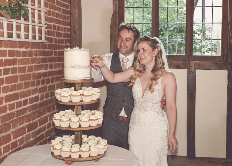 A bride and groom cutting their cake on a wedding day at Haughley Park Barn photographed by suffolk wedding photographer Hayley Denston Photography