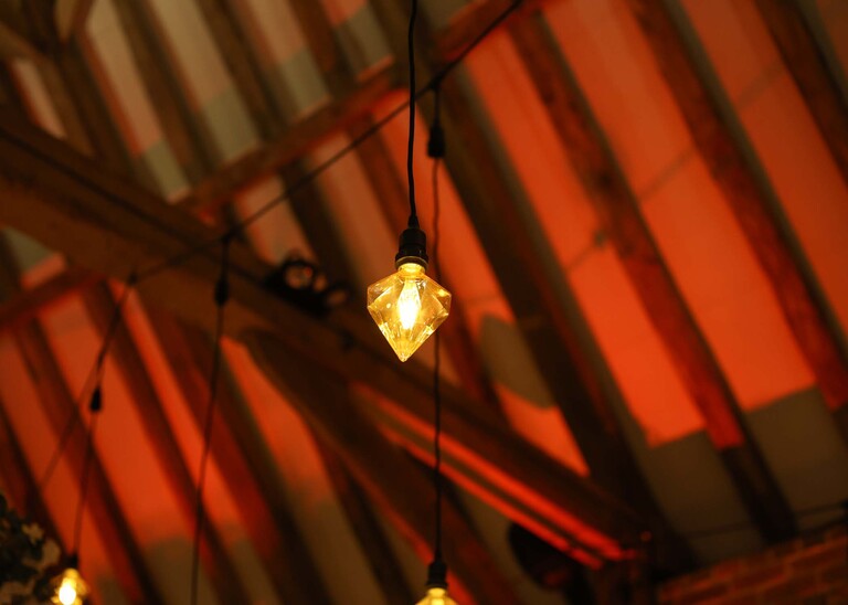 A festoon light and barn ceiling on a wedding day at Haughley Park Barn photographed by suffolk wedding photographer Hayley Denston Photography