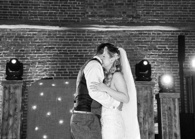 A black and white photo of a bride and groom having their first dance on a wedding day at Haughley Park Barn photographed by suffolk wedding photographer Hayley Denston Photography