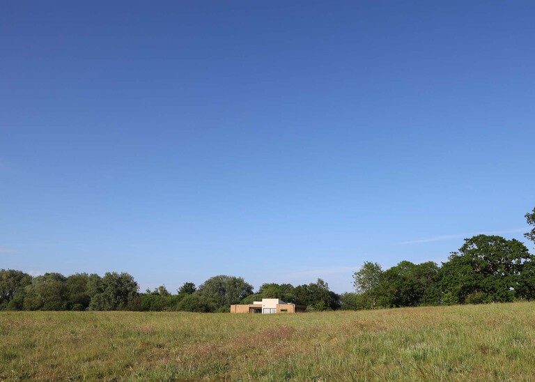 The retreat accommodation in field with blue sky on a wedding day at Little Green Wedding Barn photographed by suffolk wedding photographer Hayley Denston Photography