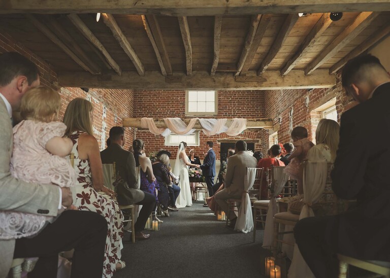 The wedding ceremony barn with the bride and groom facing each other on a wedding day at Little Green Wedding Barn photographed by suffolk wedding photographer Hayley Denston Photography