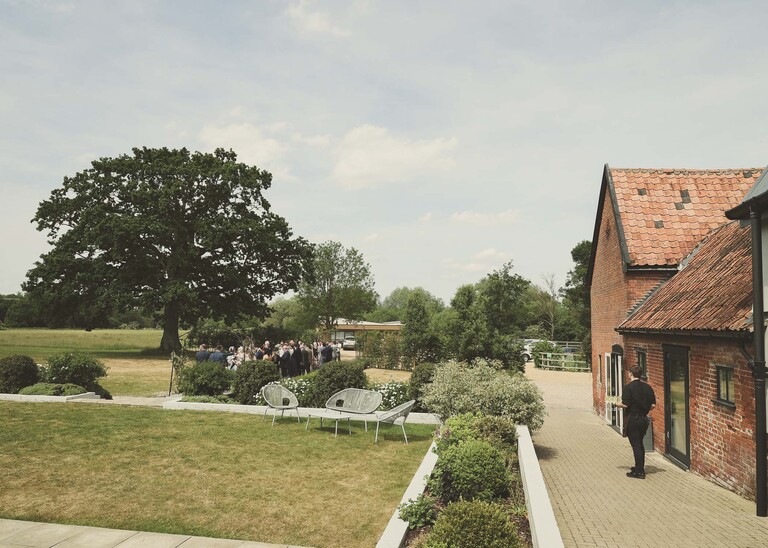 The wedding reception venue with guests mingling in the gardens on a wedding day at Little Green Wedding Barn photographed by suffolk wedding photographer Hayley Denston Photography