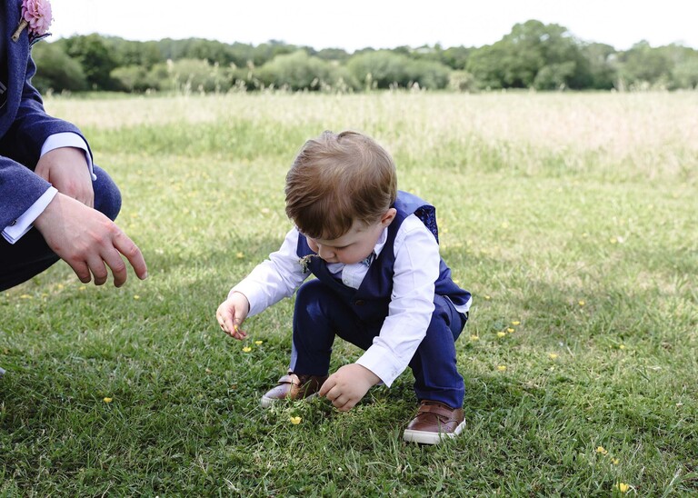 A little pageboy picking flowers on a wedding day at Little Green Wedding Barn photographed by suffolk wedding photographer Hayley Denston Photography