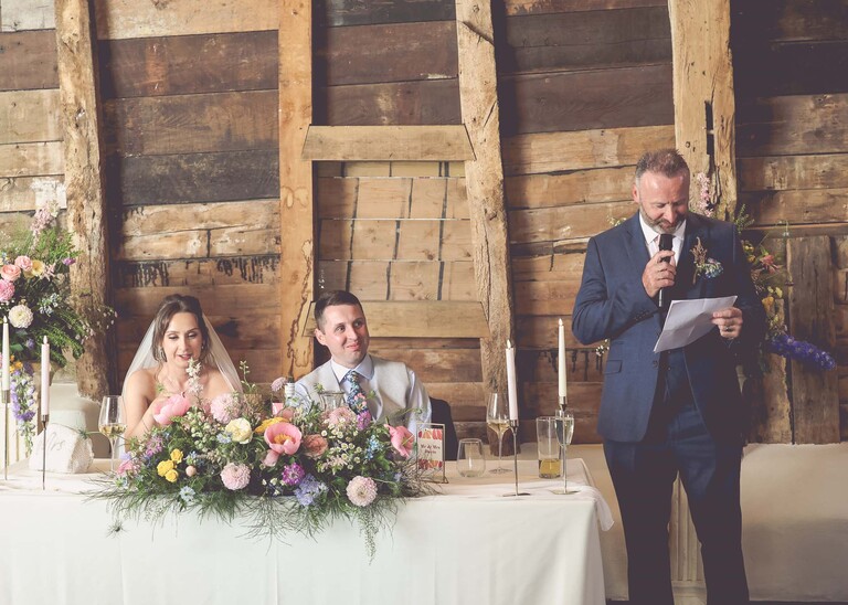 A father of the bride giving his wedding speech with rustic barn behind him on a wedding day at Little Green Wedding Barn photographed by suffolk wedding photographer Hayley Denston Photography