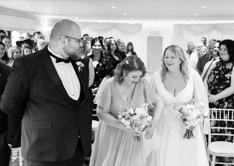 A black and white photo of the groom turning to look at his bride arriving  on a wedding day at Hungarian Hall Estate photographed by suffolk wedding photographer Hayley Denston Photography