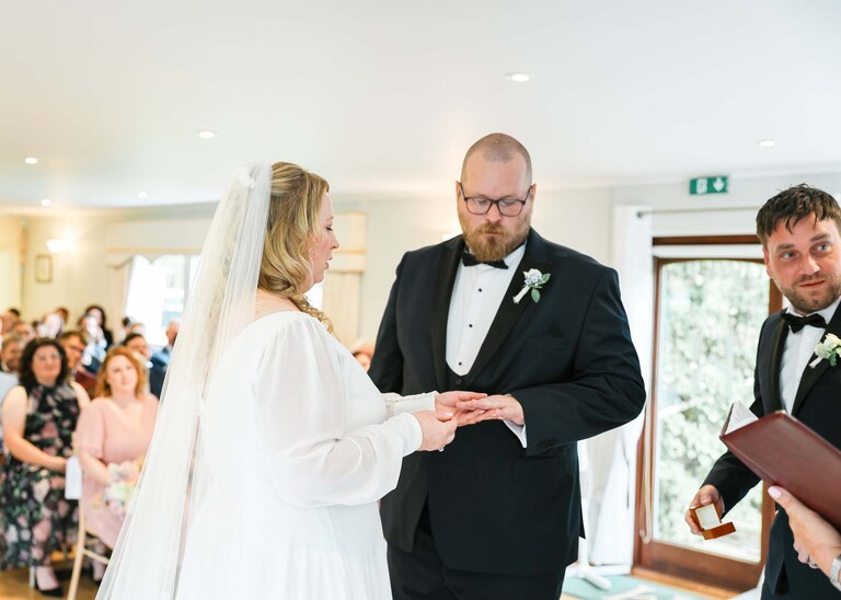 A groom putting the brides wedding ring on her finger on a wedding day at Hungarian Hall Estate photographed by suffolk wedding photographer Hayley Denston Photography