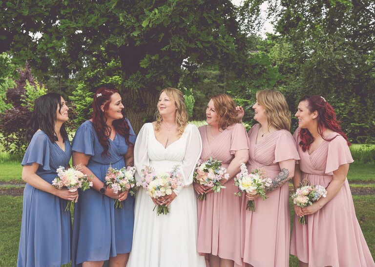 A bride and her bridesmaids chatting  on a wedding day at Hungarian Hall Estate photographed by suffolk wedding photographer Hayley Denston Photography