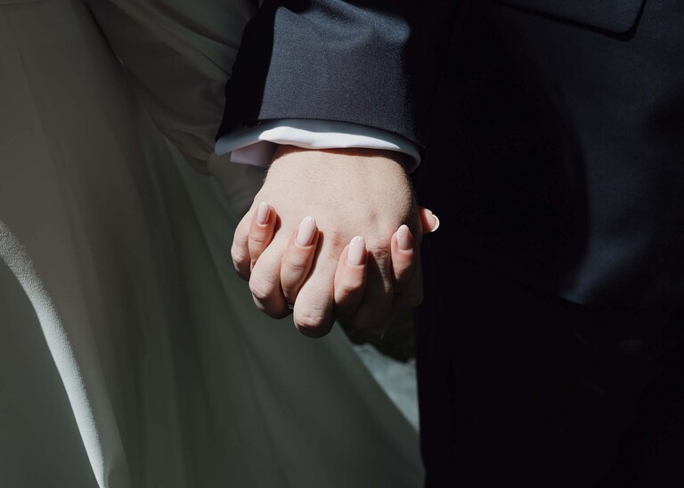 A bride and groom holding hands  on a wedding day at Hungarian Hall Estate photographed by suffolk wedding photographer Hayley Denston Photography