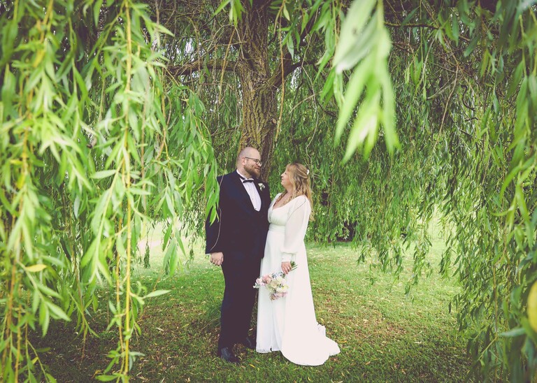 A bride and groom under a willow tree on a wedding day at Hungarian Hall Estate photographed by suffolk wedding photographer Hayley Denston Photography
