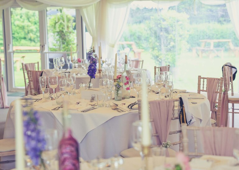 Tables set up with flowers on them on a wedding day at Hungarian Hall Estate photographed by suffolk wedding photographer Hayley Denston Photography