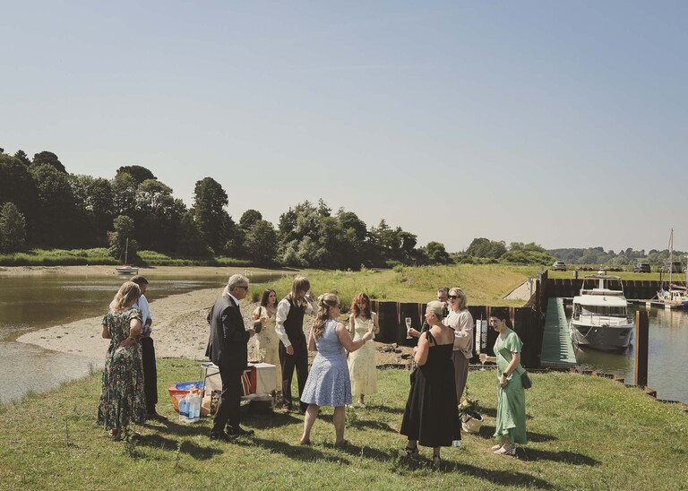 A bride and groom and their guests on the penisula at woodbridge marina on a wedding day in Woodbridge captured by Suffolk Wedding Photographer Hayley Denston Photography