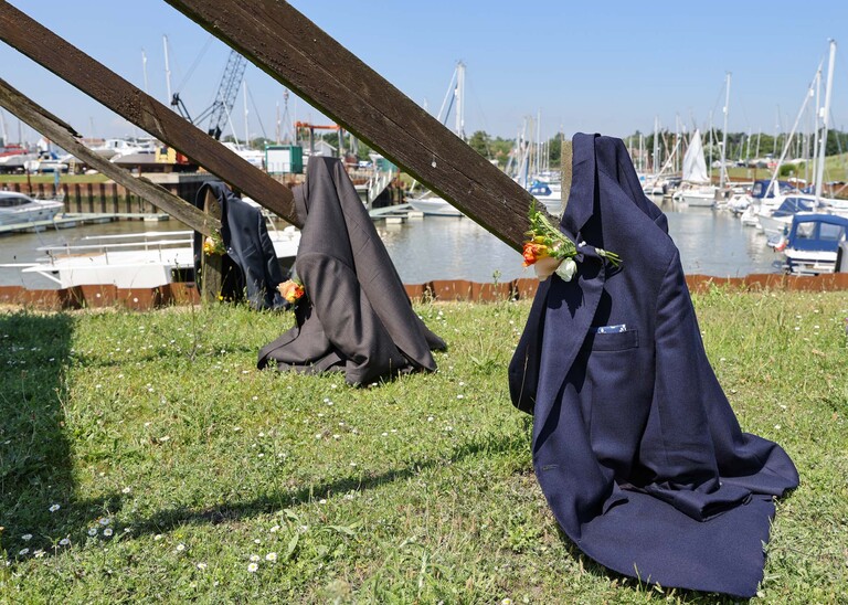Jackets hung on the yacht club sign on the penisula at woodbridge marina on a wedding day in Woodbridge captured by Suffolk Wedding Photographer Hayley Denston Photography