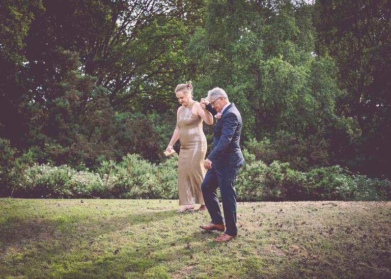 A bride and groom walking down a slope at an evening wedding reception at the Unruly Pig in Suffolk captured by Suffolk Wedding Photographer Hayley Denston Photography