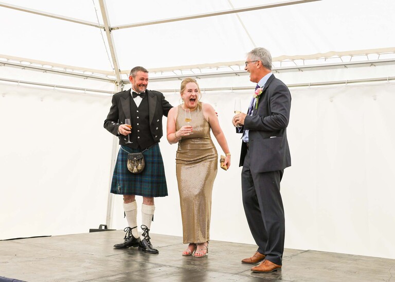 A photo of a bestman giving his speech in a marquee at an evening wedding reception at the Unruly Pig in Suffolk captured by Suffolk Wedding Photographer Hayley Denston Photography