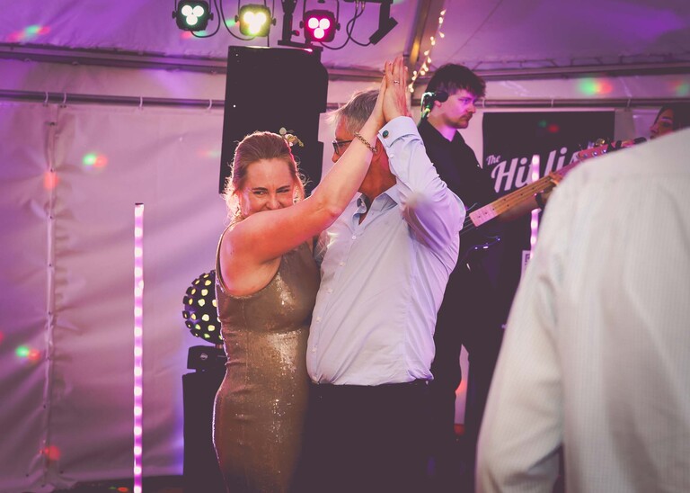 A lit marquee in gardens with everyone dancing for an evening wedding reception at the Unruly Pig in Suffolk captured by Suffolk Wedding Photographer Hayley Denston Photography